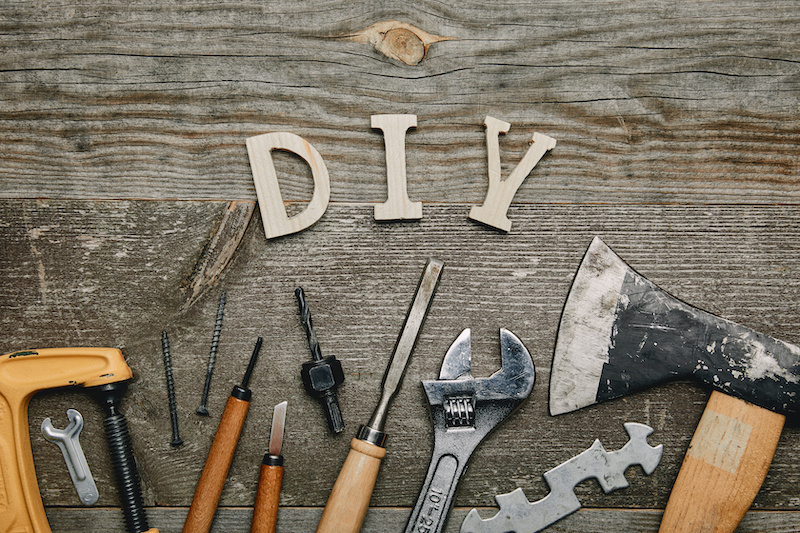 Flay lay with different carpentry tools and diy sign on wooden background