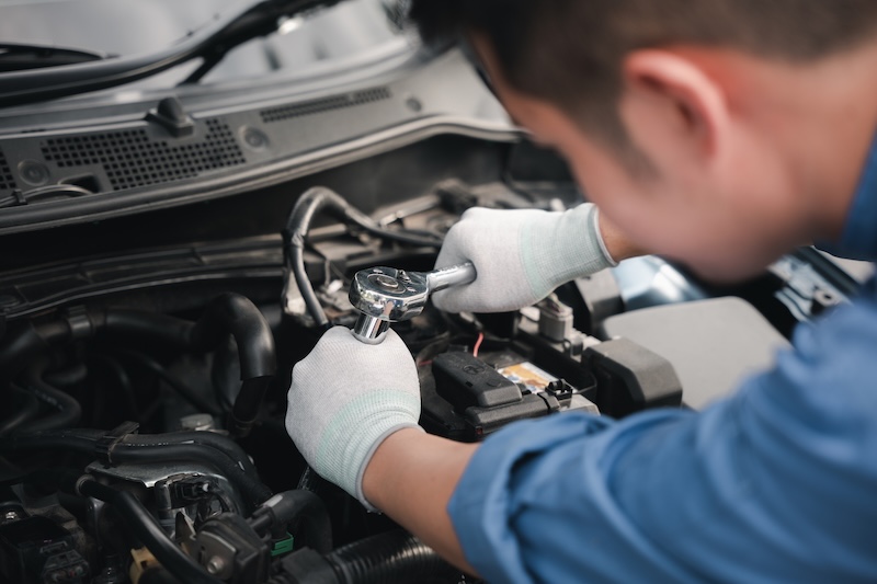 Service outdoor. Asian auto mechanic man working on car engine using wrench to repair and maintenance, broken car care check and fixed the problem and services insurance