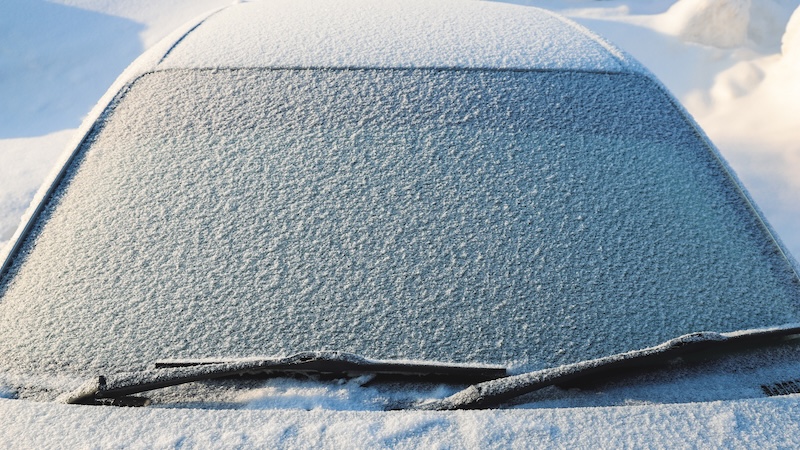Snow covered car windshield close-up. Winter. Season specific. Outdoors. Selective focus